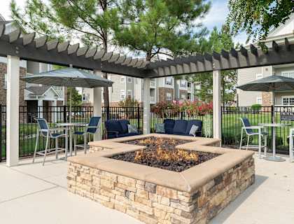 a patio with a fire pit and tables with chairs and umbrellas