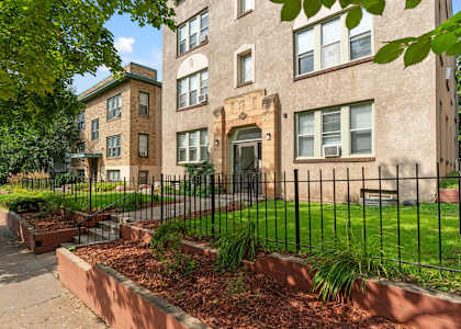 A building with a black fence and a green lawn in front.