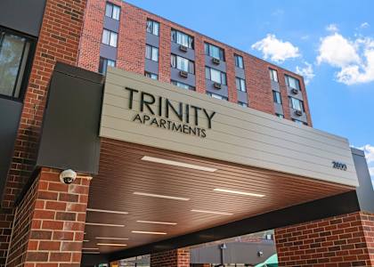 the front of a building with a trinity apartments sign