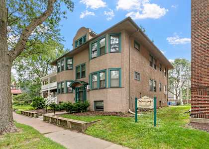 a brick building with green windows and a sidewalk in front of it