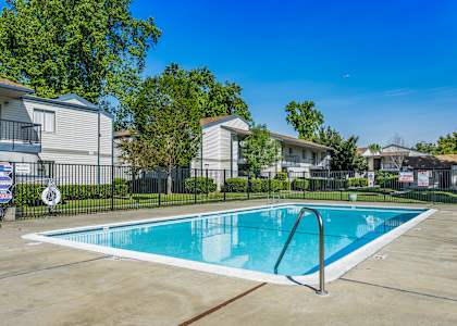 A swimming pool in a residential area with houses and trees in the background.