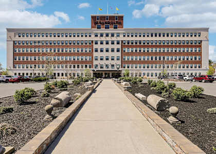 A large building with a flag on top and a walkway leading to it.