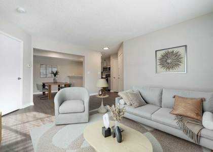A living room with a grey couch, a white coffee table, and a grey armchair.