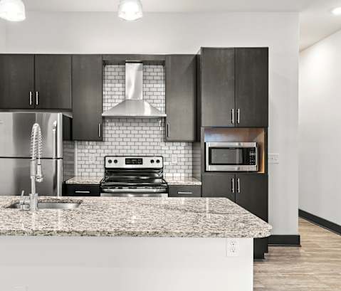 A modern kitchen with a granite countertop and stainless steel appliances.