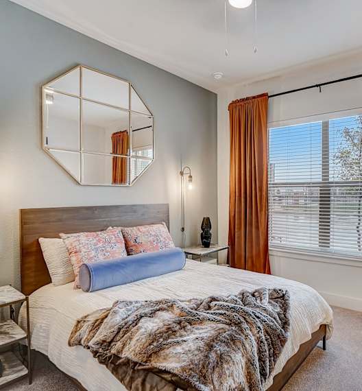 A bedroom with a large bed and a mirror on the wall.