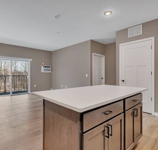 A kitchen with a white countertop and wooden cabinets.