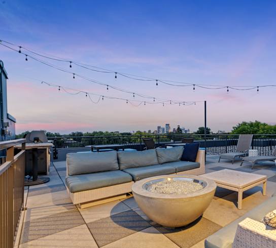 a roof deck with couches and chairs and a fire pit