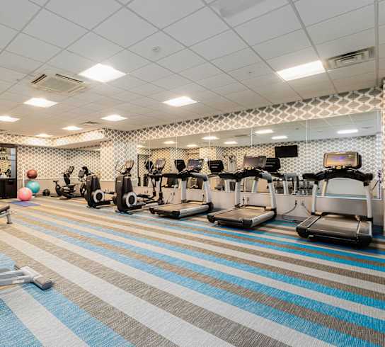 A gym with a variety of equipment including treadmills, weights, and exercise machines.