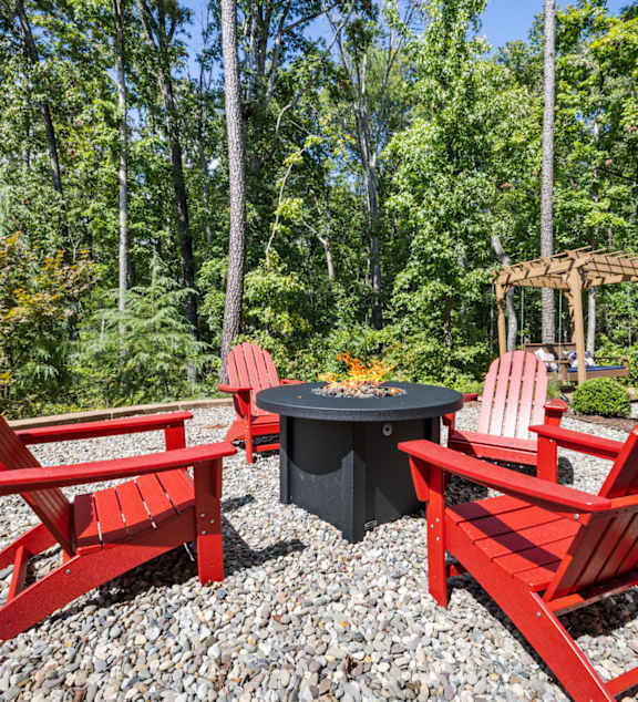a group of red chairs sitting around a table in a backyard