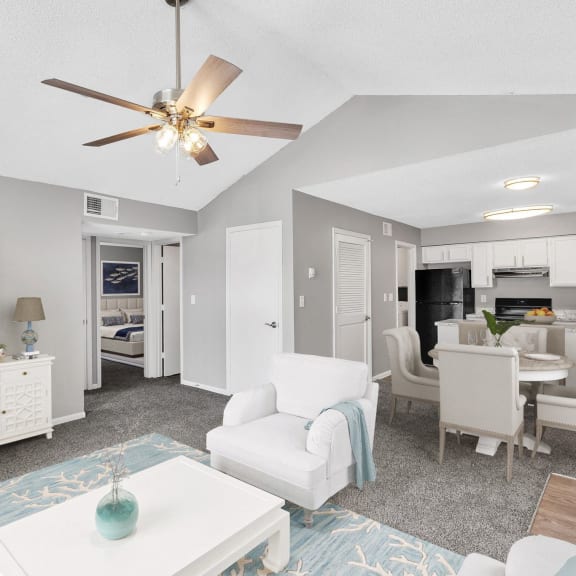 a living room with white furniture and a ceiling fan