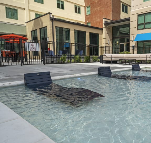 a pool with lounge chairs and umbrellas in front of a building  at The Icon, Richmond, 23230