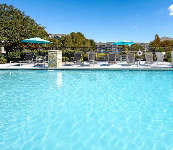 A large swimming pool with sun loungers and umbrellas.