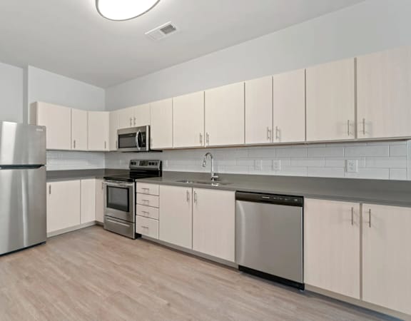 a kitchen with white cabinets and stainless steel appliances at Metropolis Apartments in Glen Allen, Virginia