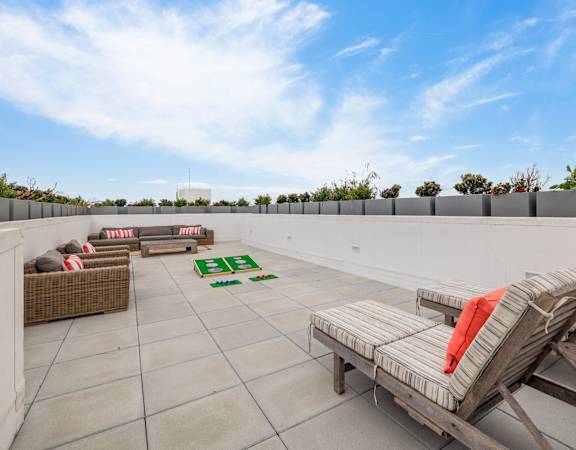 A patio with a white table and chairs and a green rug.