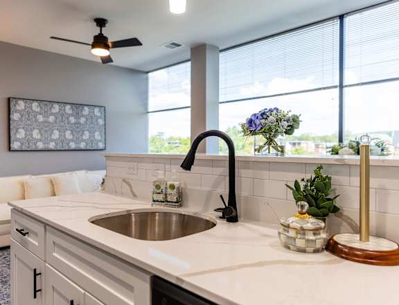 A modern kitchen with a white countertop and a large window.