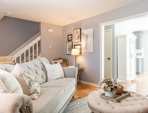 A living room with a grey couch and a round ottoman.