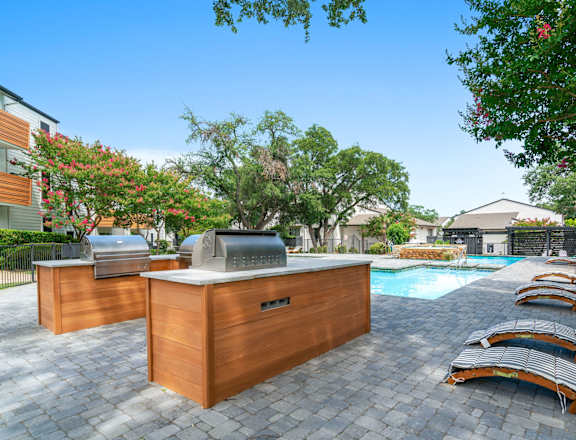 A poolside area with sun loungers and a barbecue grill.