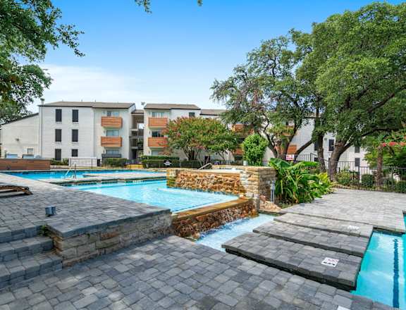 A swimming pool surrounded by stone steps and lounge chairs.