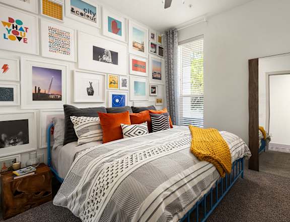 A bedroom with a bed, pillows, and pictures on the wall.