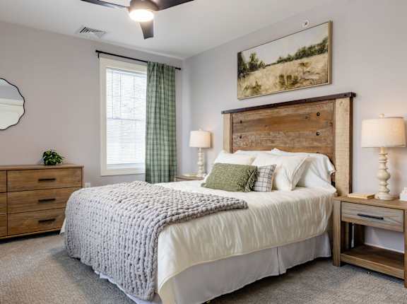 A bedroom with a large bed, a wooden headboard, and a painting on the wall.