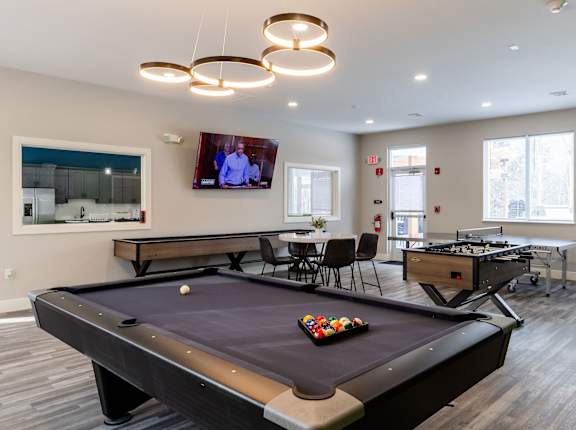 A pool table in a room with a television mounted on the wall.