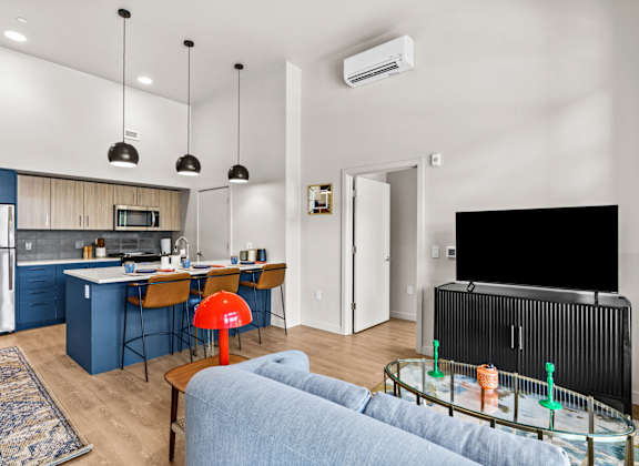 A modern kitchen with blue cabinets and a black fridge.