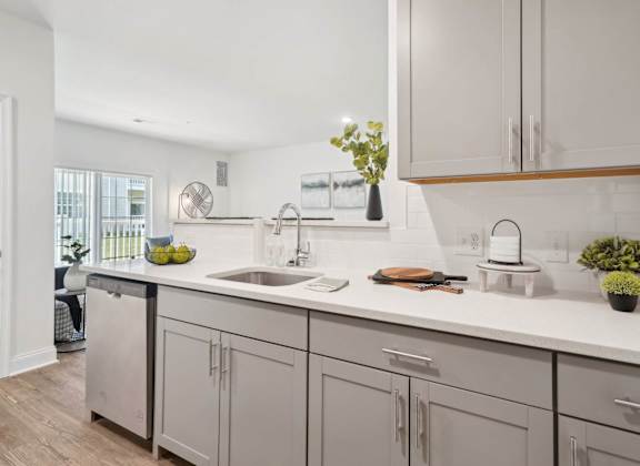 A kitchen with a white counter top and grey cabinets.