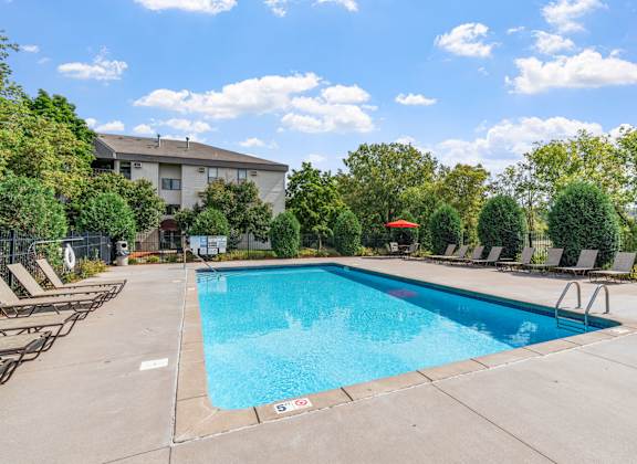 a swimming pool with chairs and a building in the background