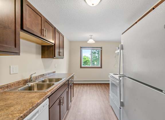 a kitchen with a sink and refrigerator and a window