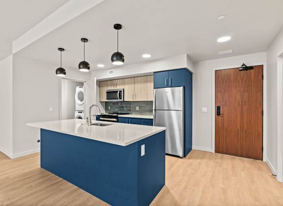 A kitchen with a blue island and stainless steel appliances.