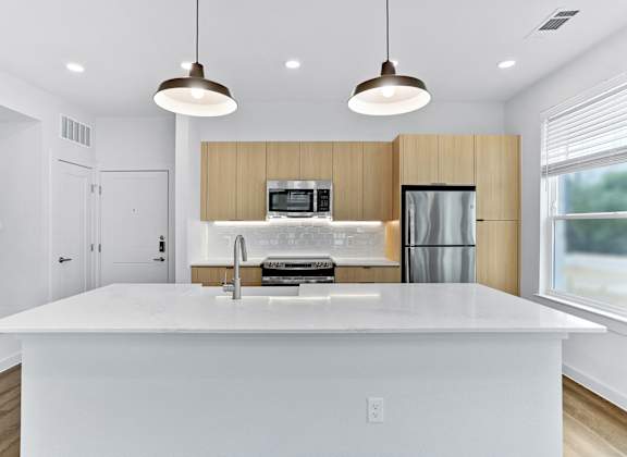 A modern kitchen with a large island and pendant lights.