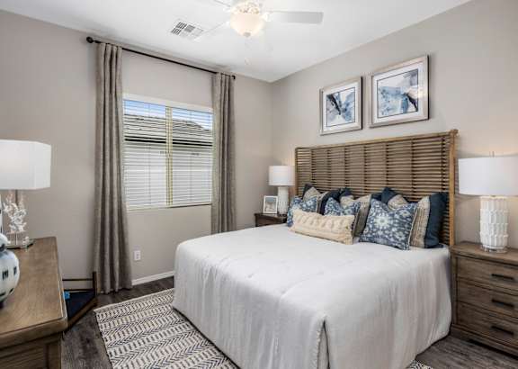 A bedroom with a large bed, a nightstand with a lamp, and two pictures on the wall.