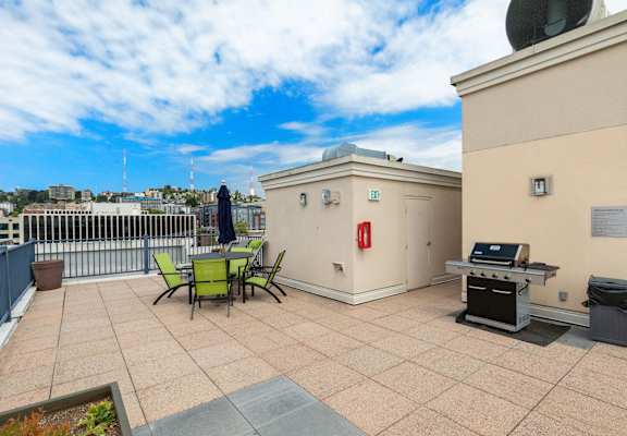 a rooftop patio with a grill and a table and chairs