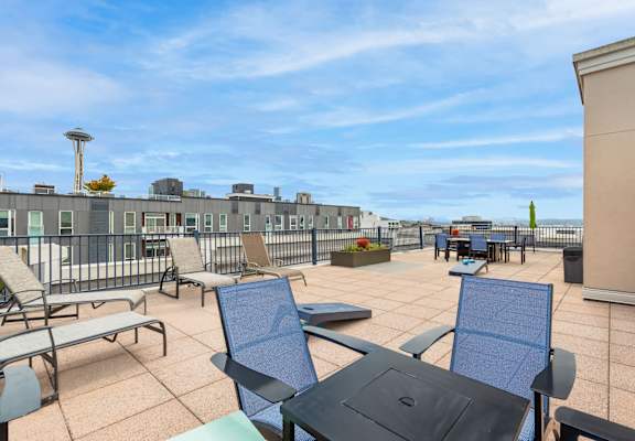 a rooftop patio with chairs and tables and a view of the ocean