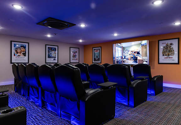 a theater room with blue chairs and a projector screen