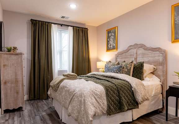 A bedroom with a large bed and a window with curtains.