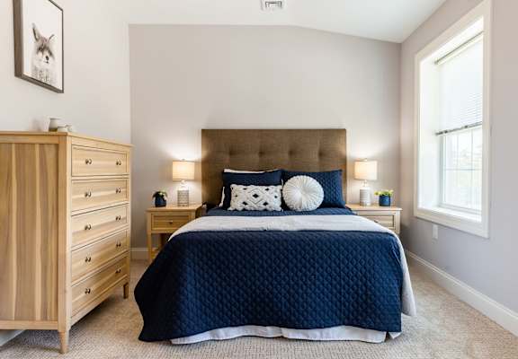 A bedroom with a large bed and a wooden dresser.