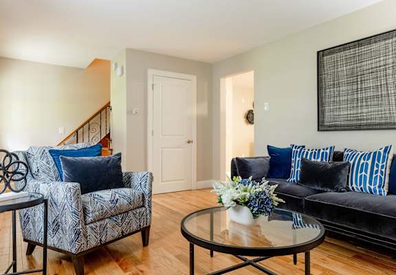 A living room with a black couch and a blue and white patterned chair.
