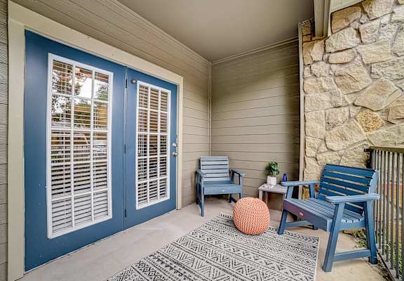 front porch with two chairs and a table with a potted plant