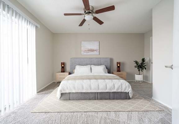 A bedroom with a large bed and a ceiling fan.