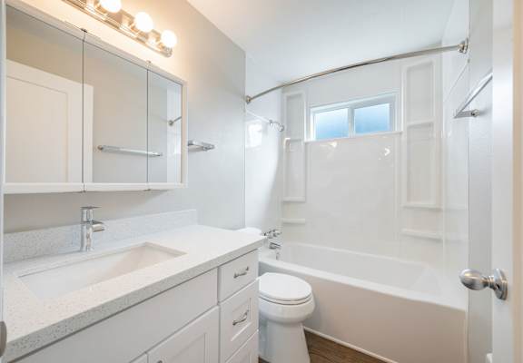 A white bathroom with a toilet, sink, and bathtub.