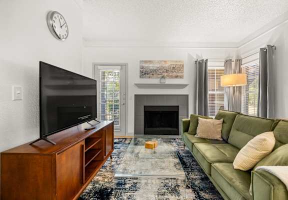 A living room with a green couch and a fireplace.