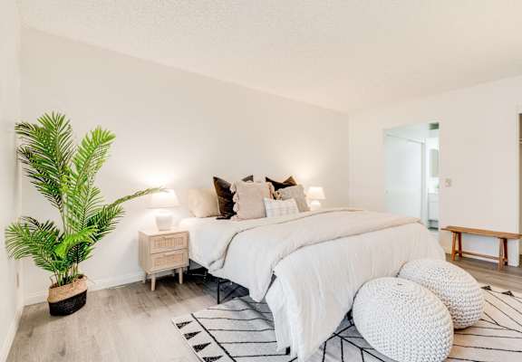 a bedroom with a large bed and a potted plant