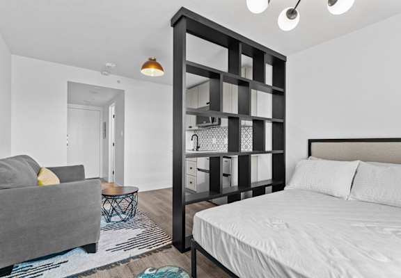 A bedroom with a large bed and a grey couch.