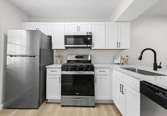 A modern kitchen with white cabinets and stainless steel appliances.