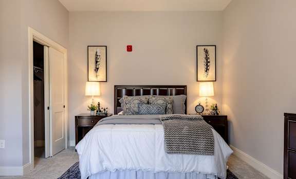 A bedroom with a large bed and two wall lamps.