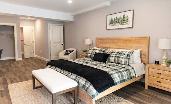 A bedroom with a large bed and a bench in front of it.