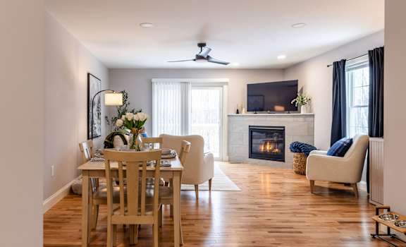 A living room with a fireplace and a dining table.