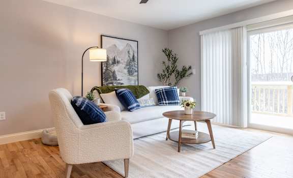 A living room with a white chair, a white couch, and a wooden coffee table.