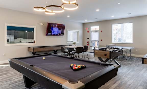 A pool table in a room with a television mounted on the wall.